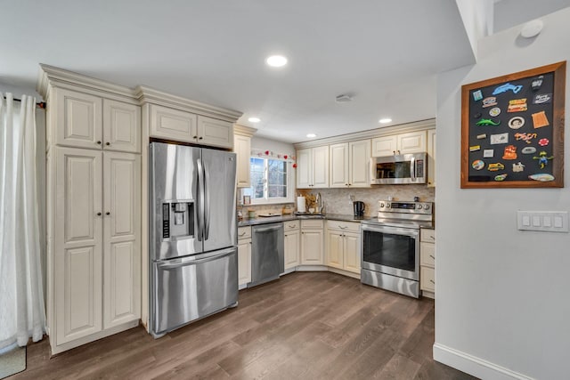 kitchen with tasteful backsplash, dark countertops, dark wood-style floors, stainless steel appliances, and cream cabinetry