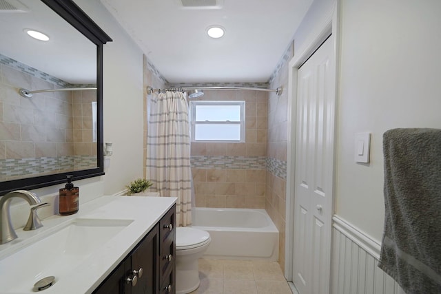 bathroom featuring tile patterned flooring, toilet, vanity, wainscoting, and shower / tub combo with curtain