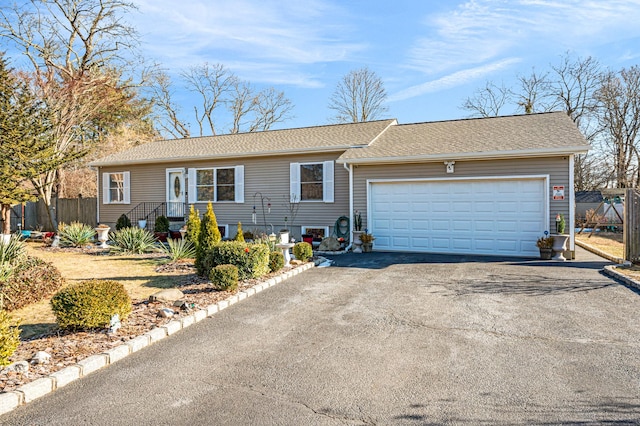 ranch-style home with a garage, driveway, a shingled roof, and fence