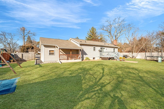 back of house featuring a fenced backyard, a lawn, a playground, and a wooden deck