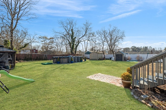 view of yard with a fenced in pool, an outdoor structure, fence, and a shed