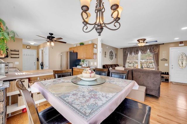 dining area with light wood finished floors and ceiling fan with notable chandelier