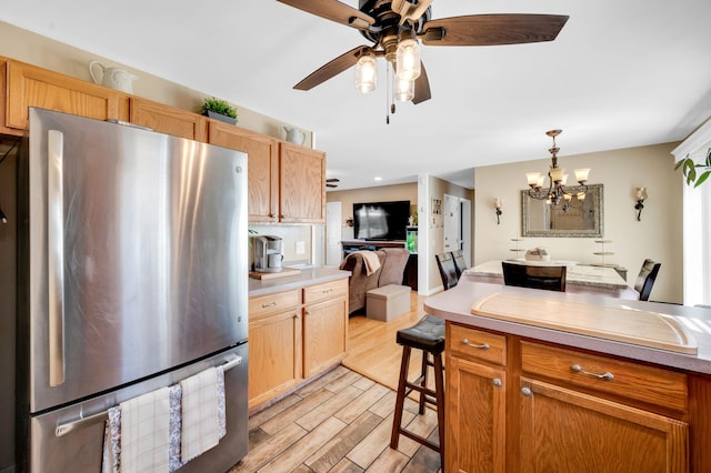 kitchen with decorative light fixtures, light countertops, light wood-style flooring, freestanding refrigerator, and open floor plan