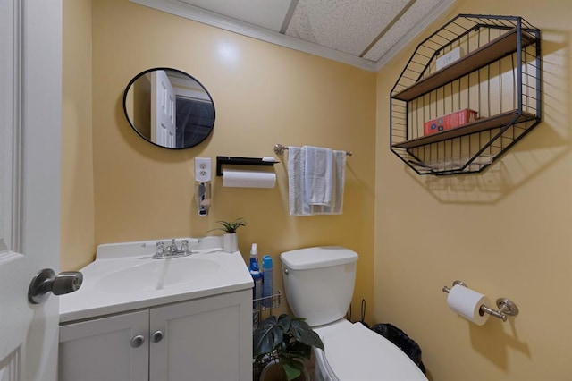 half bath with ornamental molding, vanity, and toilet