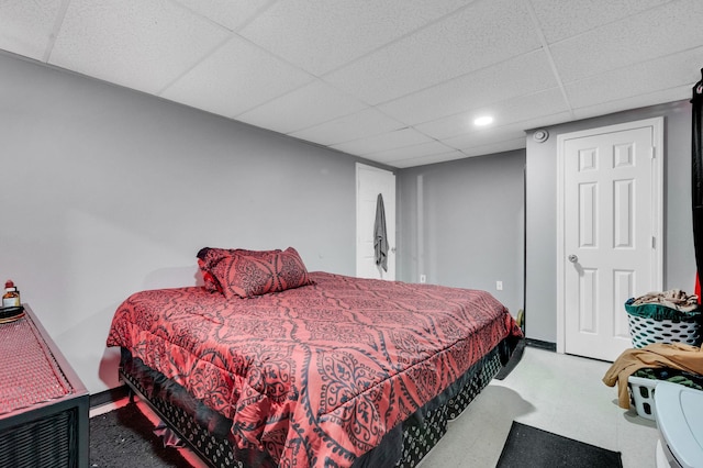 bedroom with a drop ceiling, baseboards, and tile patterned floors