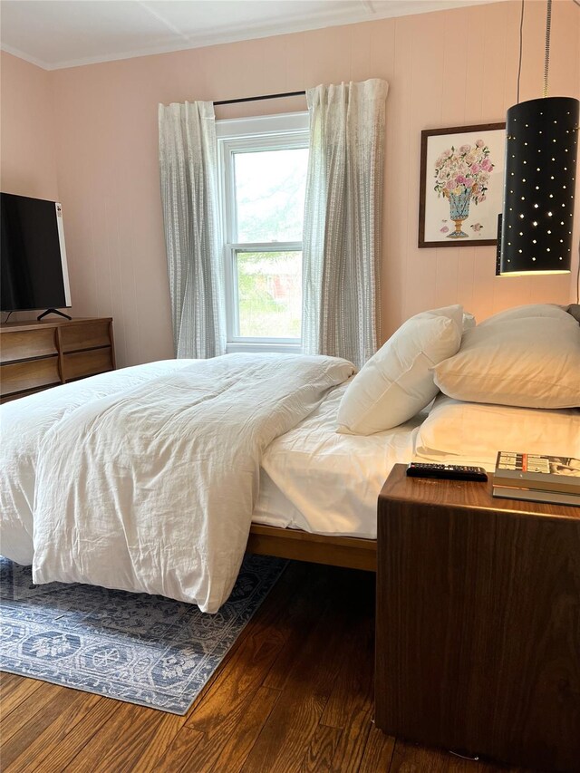 bedroom featuring ornamental molding and wood finished floors