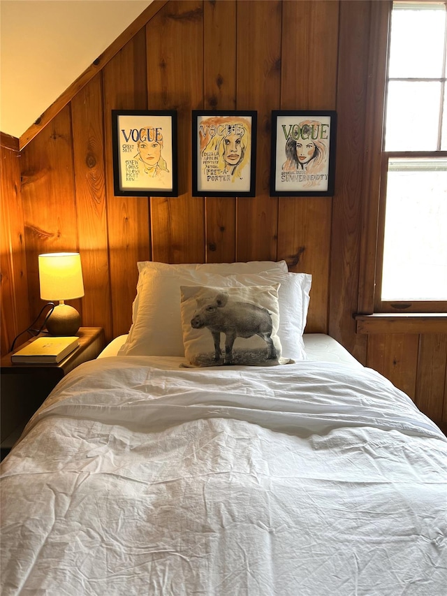 bedroom featuring vaulted ceiling and wooden walls