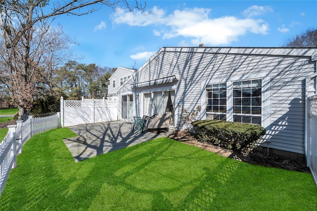 rear view of property with a fenced backyard, a lawn, and a patio