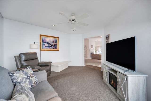 living room featuring recessed lighting, light colored carpet, ceiling fan, and a lit fireplace