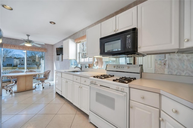 kitchen featuring light countertops, light tile patterned flooring, a sink, white cabinets, and white appliances