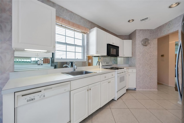 kitchen featuring white appliances, wallpapered walls, light countertops, white cabinetry, and a sink