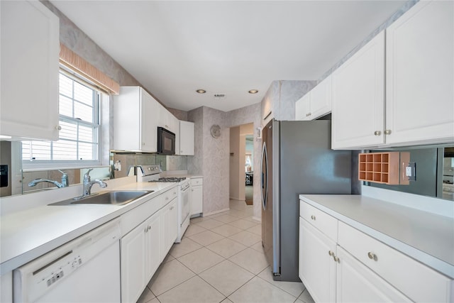 kitchen featuring light tile patterned floors, light countertops, white cabinetry, a sink, and white appliances