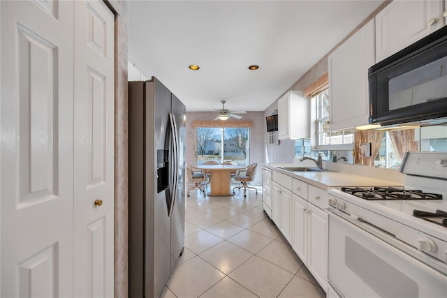 kitchen featuring white appliances, white cabinets, light countertops, a sink, and light tile patterned flooring