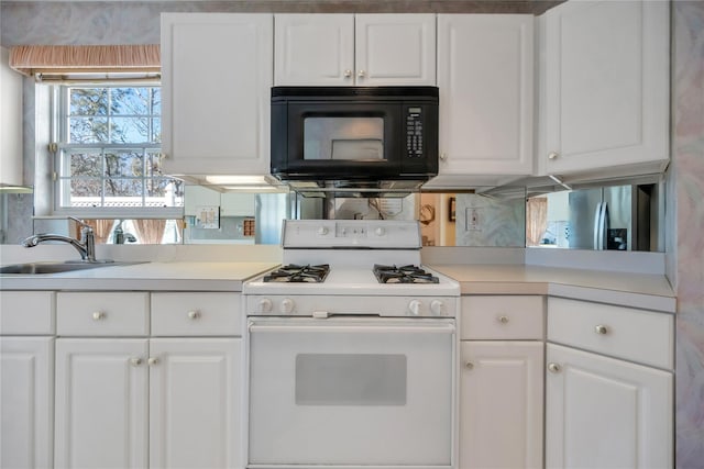 kitchen with black microwave, white cabinetry, and white gas range oven