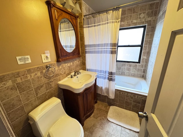 bathroom with toilet, tiled shower / bath, tile walls, and vanity