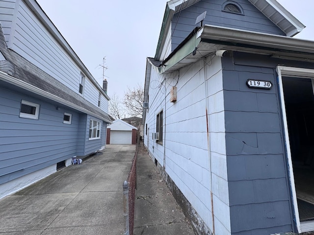 view of side of property featuring an outbuilding, concrete driveway, and a detached garage