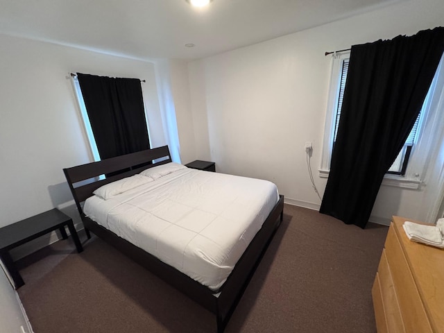 bedroom featuring dark colored carpet and baseboards