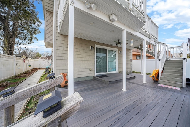 wooden deck with a ceiling fan, a fenced backyard, and stairs