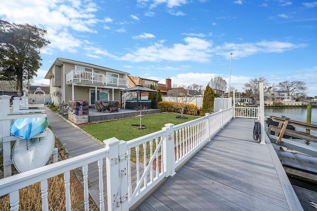 dock area with a water view, fence, a gazebo, a lawn, and a residential view