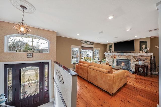 living room featuring light wood finished floors, recessed lighting, visible vents, and a stone fireplace