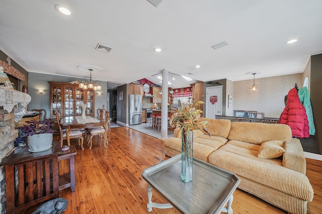 living room featuring an inviting chandelier, light wood-style flooring, visible vents, and recessed lighting