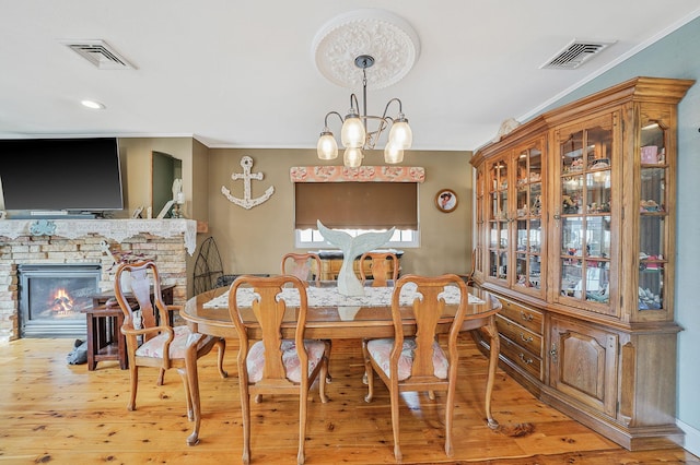 dining area featuring a chandelier, ornamental molding, a fireplace, and visible vents