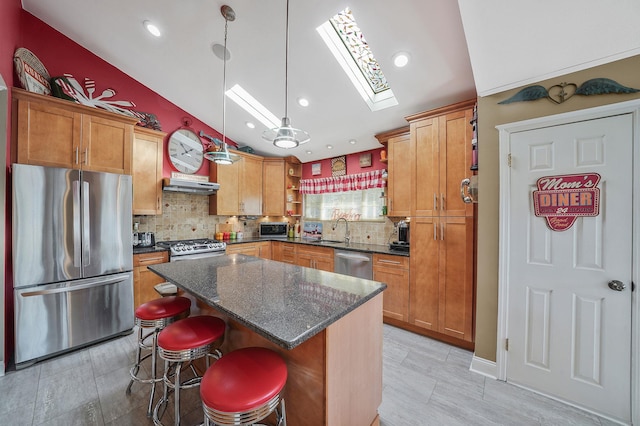 kitchen featuring a center island, pendant lighting, appliances with stainless steel finishes, a sink, and under cabinet range hood