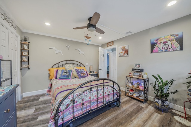 bedroom featuring a ceiling fan, wood finished floors, visible vents, and baseboards