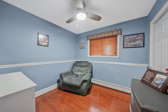 living area with a ceiling fan, baseboards, baseboard heating, and wood finished floors