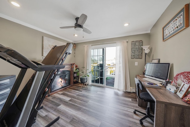 office with ornamental molding, light wood-type flooring, and a glass covered fireplace