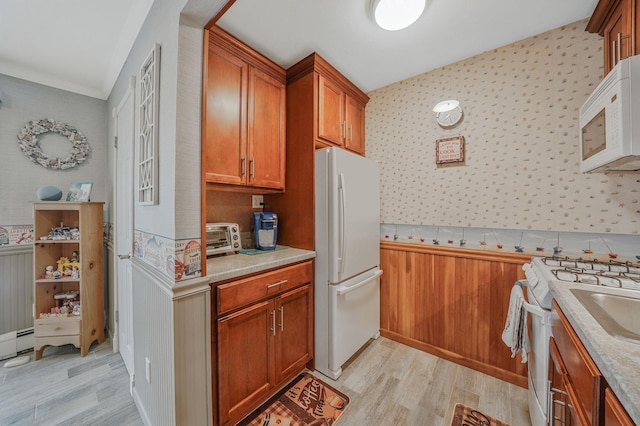 kitchen featuring white appliances, a toaster, wallpapered walls, brown cabinets, and light wood-type flooring