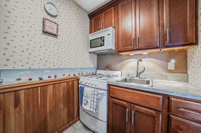 kitchen featuring white appliances, tasteful backsplash, light countertops, and a sink