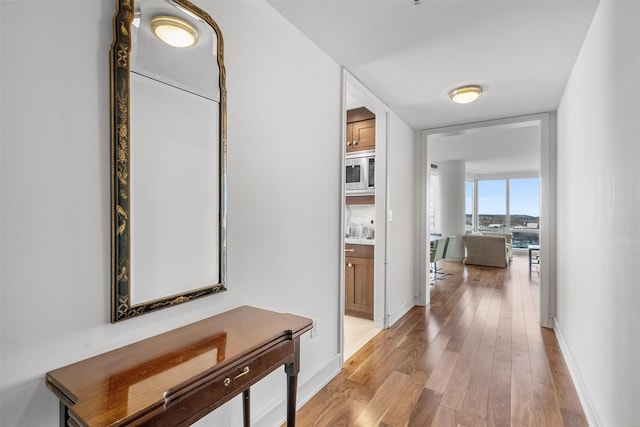 hallway featuring light wood finished floors and baseboards