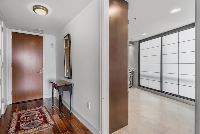 hallway with light wood-style floors, recessed lighting, visible vents, and baseboards