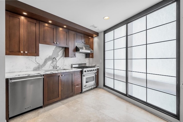 kitchen featuring under cabinet range hood, stainless steel appliances, a sink, backsplash, and light stone countertops