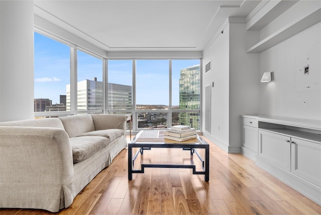 living area featuring a healthy amount of sunlight, light wood-style floors, visible vents, and a city view