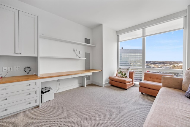 home office featuring a view of city, light colored carpet, built in study area, a wall of windows, and baseboards