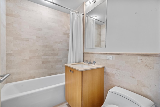 bathroom with wainscoting, toilet, shower / tub combo with curtain, vanity, and tile walls