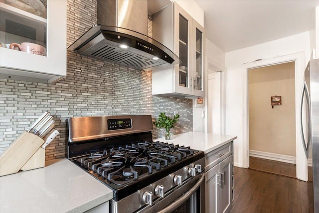 kitchen with wall chimney range hood, appliances with stainless steel finishes, light countertops, and backsplash