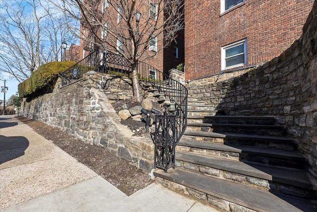 exterior space featuring stone siding, stairs, and brick siding