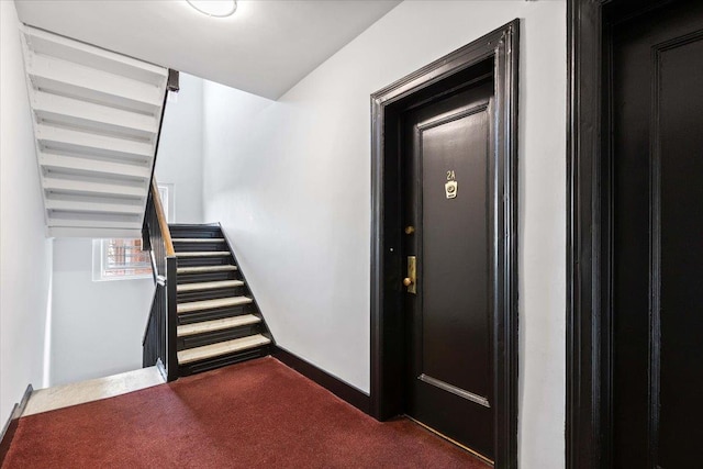 stairway featuring carpet flooring and baseboards