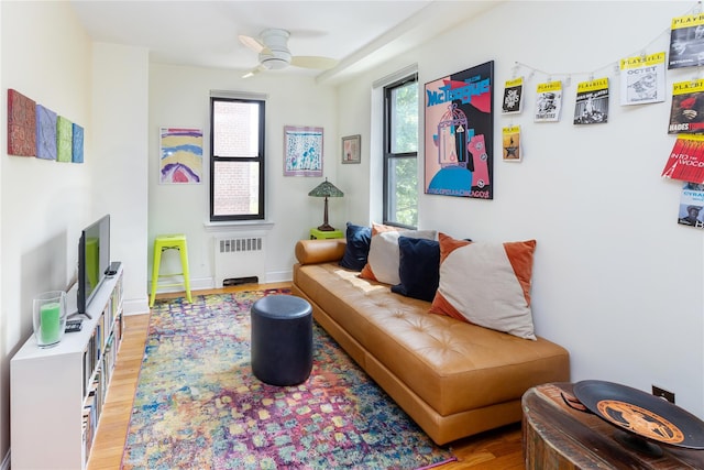 living room with ceiling fan, radiator heating unit, light wood-style flooring, and baseboards