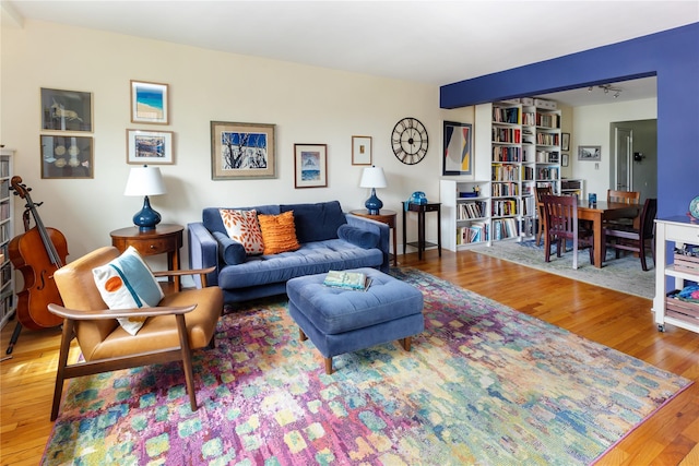 living area featuring beam ceiling and wood finished floors