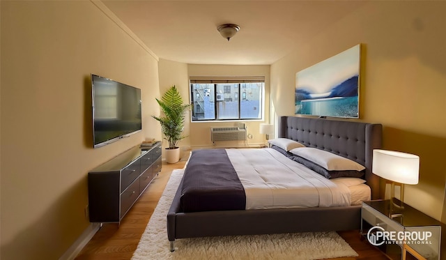 bedroom with a wall mounted air conditioner and wood finished floors