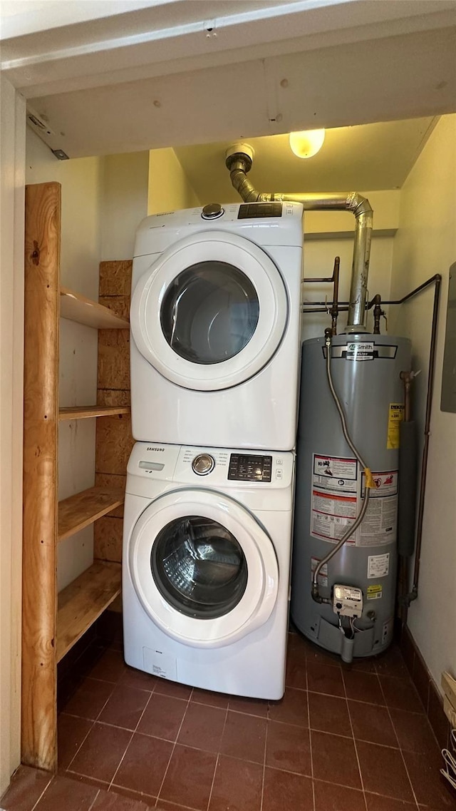 washroom with water heater, laundry area, dark tile patterned flooring, and stacked washer / drying machine