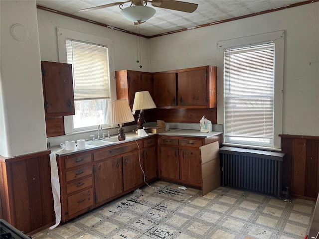 kitchen featuring radiator, light countertops, a sink, and light floors