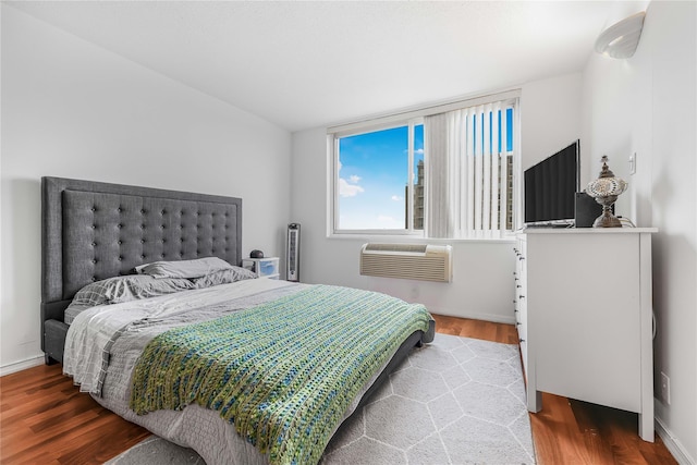 bedroom with a wall unit AC and wood finished floors