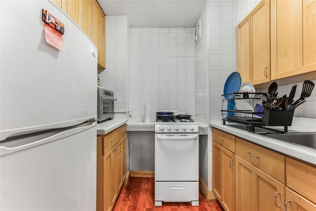 kitchen featuring white appliances, decorative backsplash, dark wood-style flooring, light countertops, and tile walls