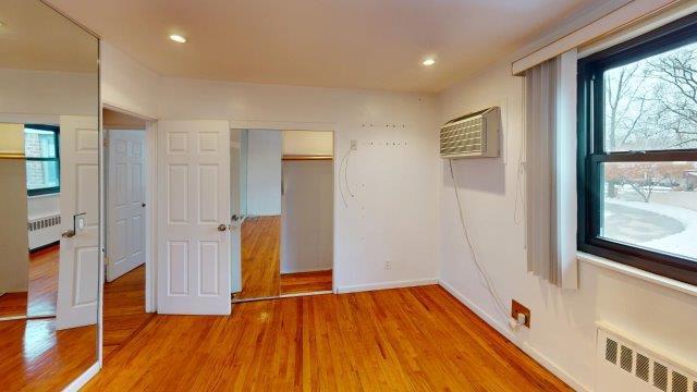 unfurnished bedroom with light wood finished floors, radiator heating unit, and recessed lighting