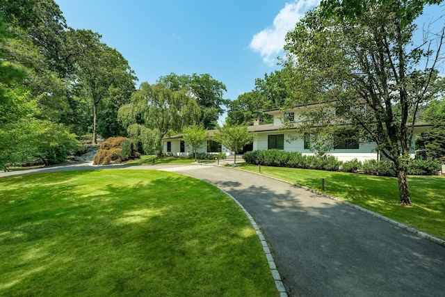 surrounding community with driveway and a lawn